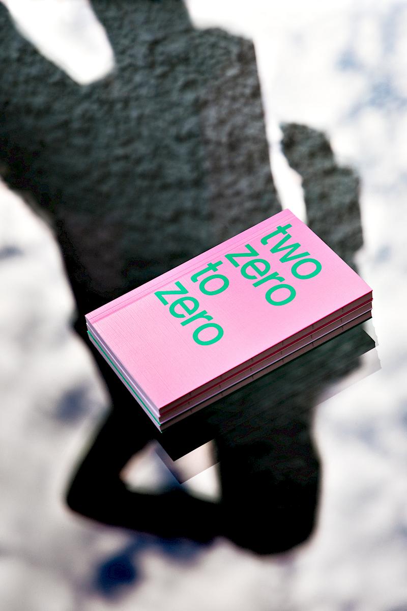 A woman’s shadow casted on a pink planner lying on a glass surface reflecting some clouds