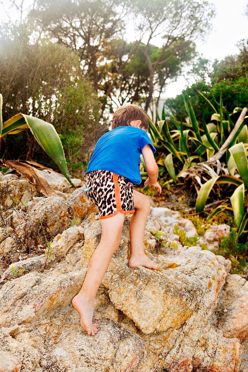 A boy climbing a rock barefoot