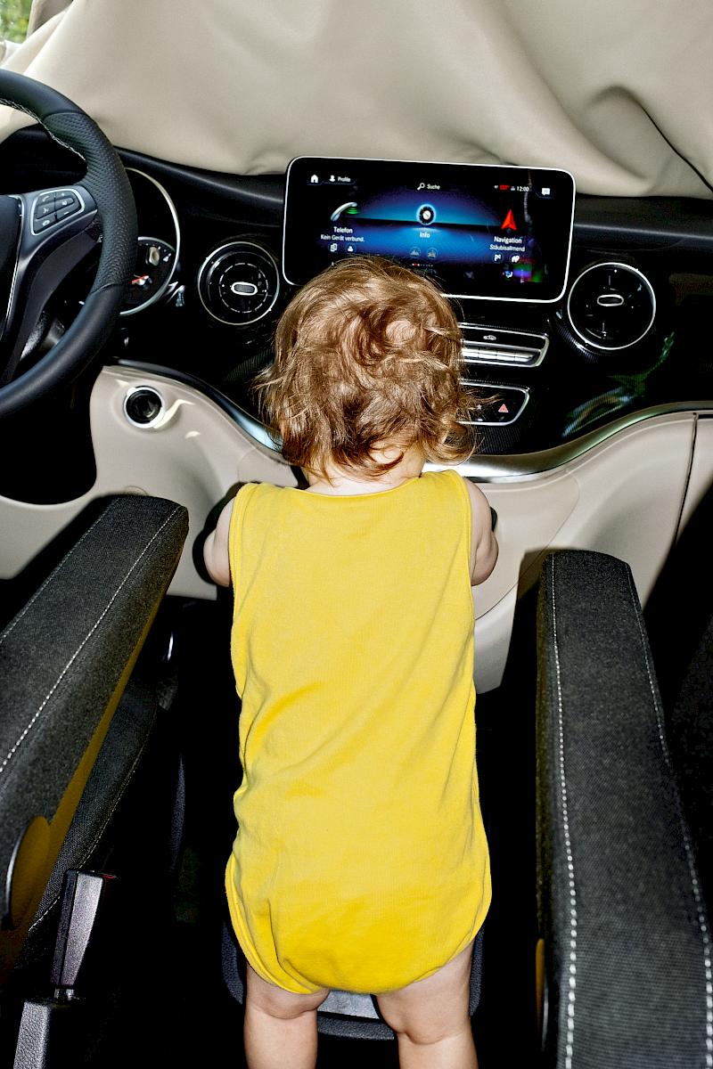 Toddler in a yellow bodysuit playing with the Mercedes Marco Polo centre console