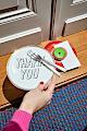 A woman's hand holding a Bitossi Home Thank you plate near a Serax Dé off-white/red plate in front of a hay door mat