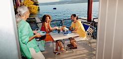 A group of people enjoying a meal on a patio overlooking a lake