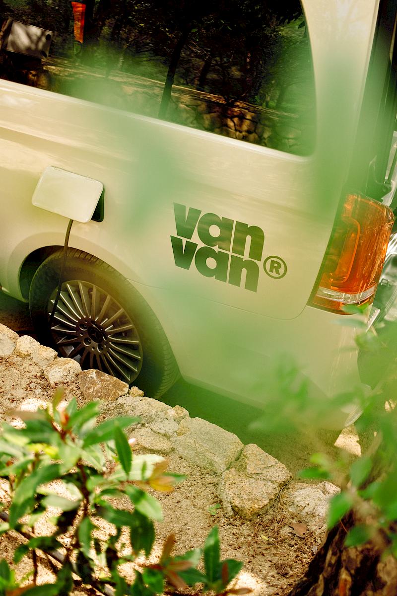 Van parked behind green foliage